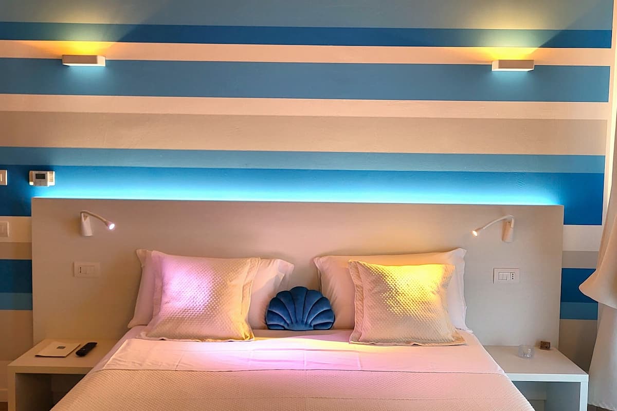 Una habitación de hotel con una cama, mesitas de noche y un diseño de pared a rayas.