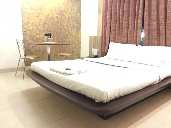 A hotel room with a bed, a desk with chairs, and a small table with toiletries.
