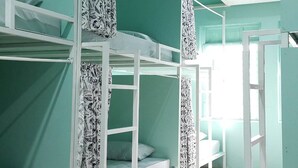 Ein Zimmer mit Etagenbetten, einer weißen Leiter und einem Fenster mit Vorhängen.