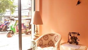 Ein Zimmer mit Fenster, einer Lampe, einem Stuhl und einem Tisch mit Telefon.
