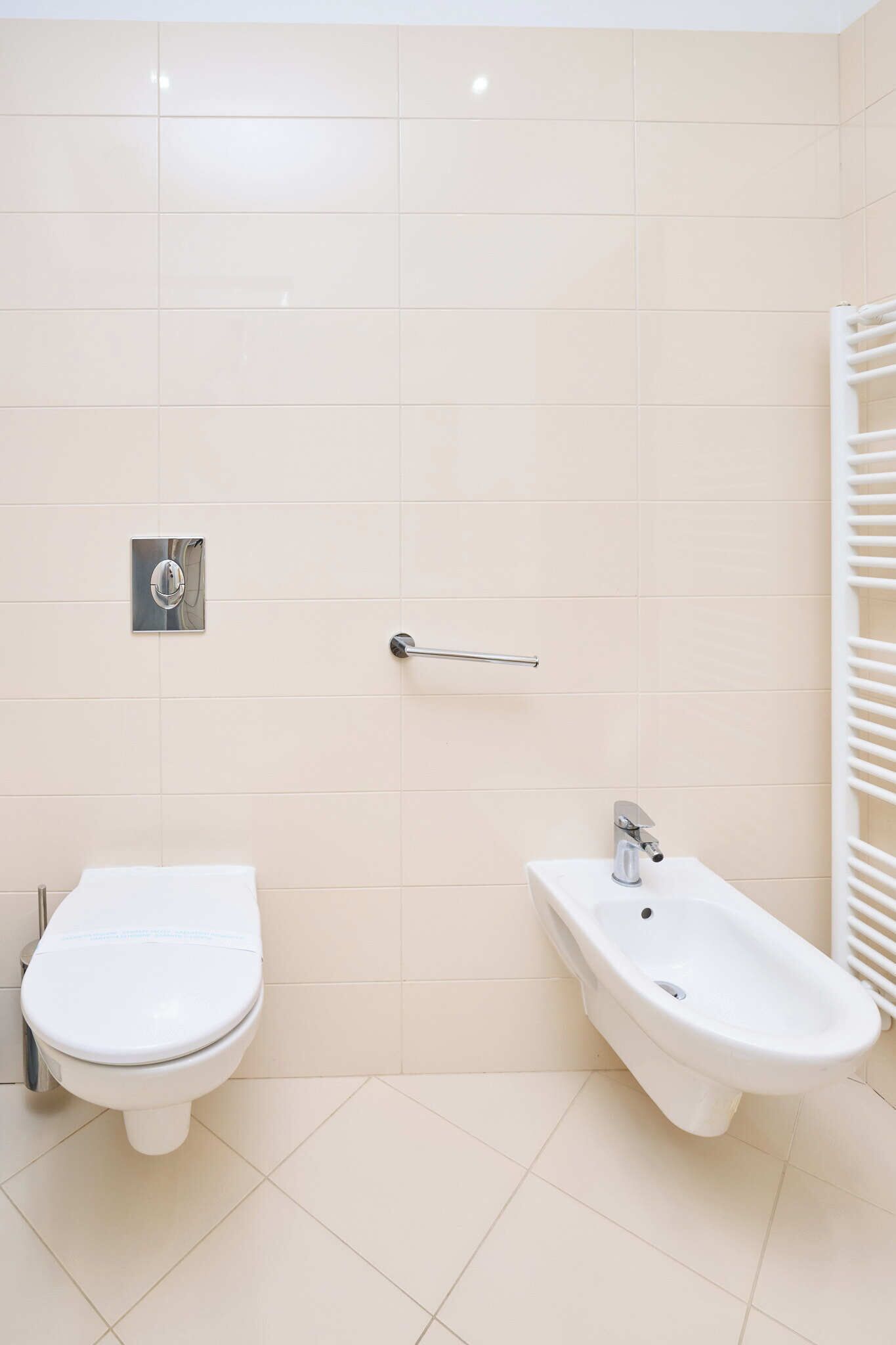 Une salle de bain équipée de toilettes, d’un bidet et d’un porte-serviettes.