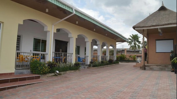 A building with a covered walkway and a thatched-roof structure. - Best Budget Hotel (Abuja)