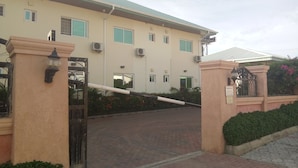 A building with a beige facade, multiple windows, and a gated entrance. - Best Budget Hotel (Abuja)