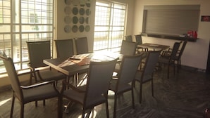 A dining area with a table and chairs, large windows, and a wall-mounted TV. - Best Budget Hotel (Abuja)