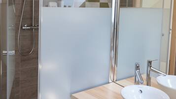 Une salle de bain moderne avec une douche à parois de verre, un meuble-lavabo en bois doté de deux vasques et un grand miroir.