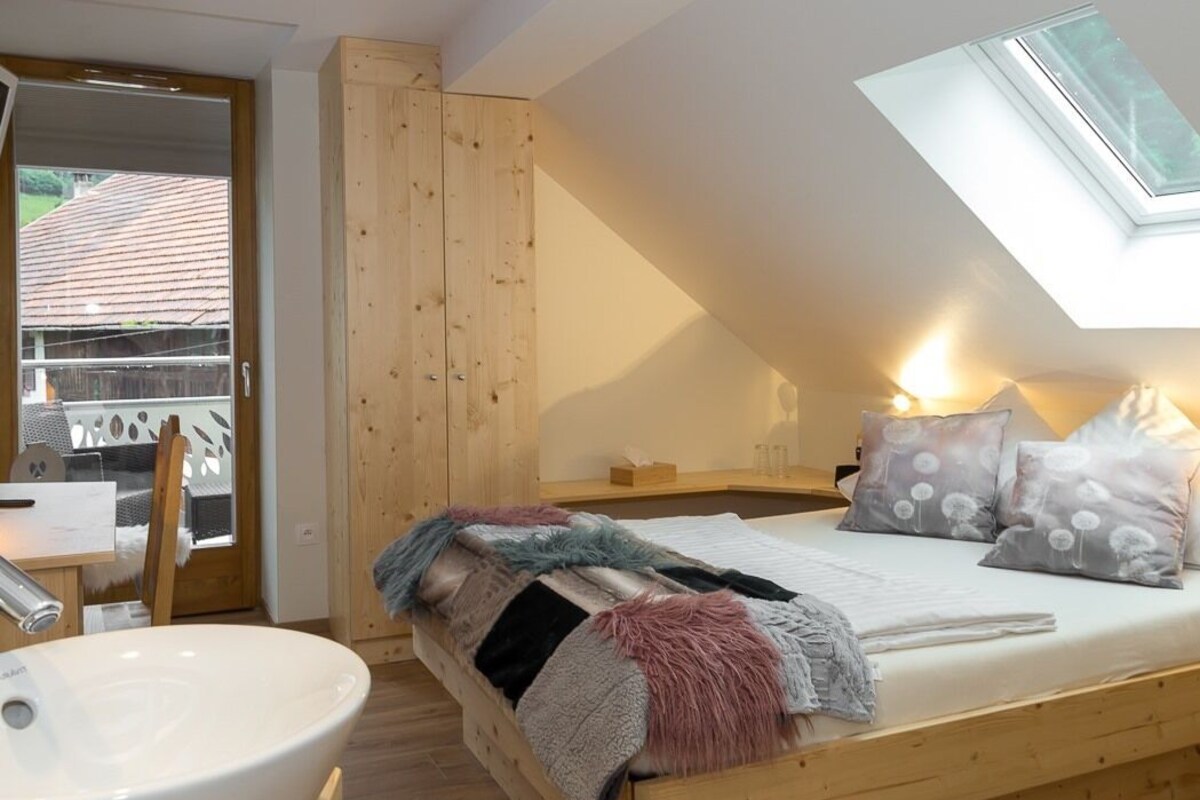A bedroom with a skylight, a wooden bed, a bedside table, and a view of the outside.