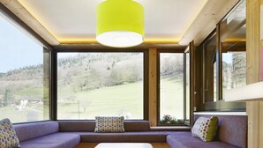 Un interior moderno con techo de madera, ventanas amplias, un conjunto de sofá y una mesa blanca.