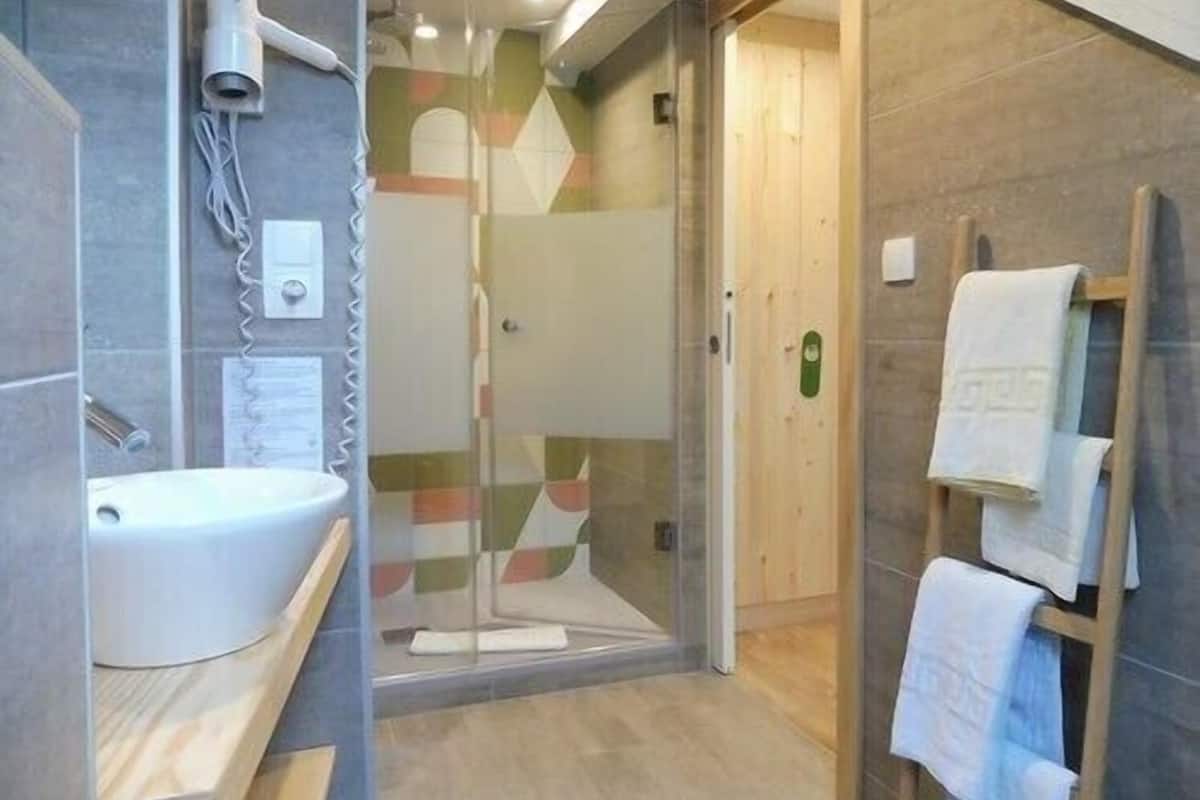 A modern bathroom with a glass shower enclosure, a sink, and a towel rack.