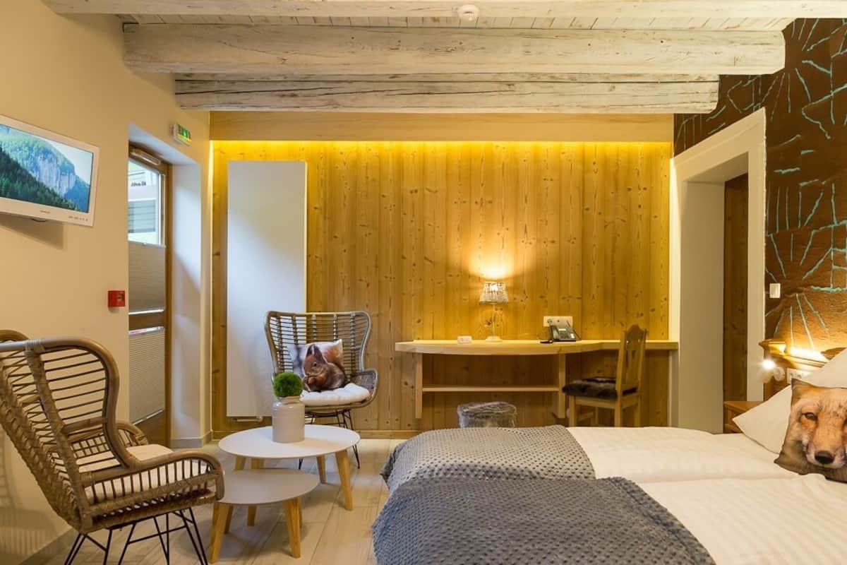 A cozy room with a bed, a chair, a small table, and a desk.