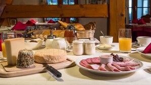 Una mesa de desayuno con diversos alimentos, como queso, pan y embutidos.