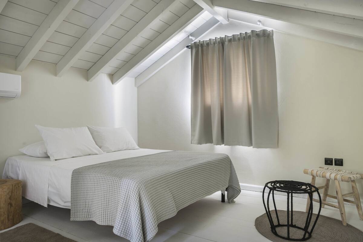Ein Schlafzimmer mit einem Bett, einem runden Tisch und einem Fenster mit Vorhängen.