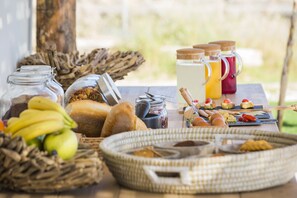 A breakfast setup with bread, bananas, eggs, and various condiments on a wooden table. - Kymata Bohemian Beach Resort (Kefalonia)