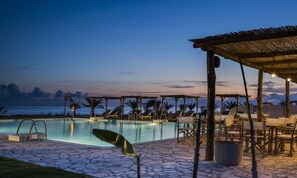 A poolside area with lounge chairs and a covered seating area, overlooking a body of water. - Kymata Bohemian Beach Resort (Kefalonia)
