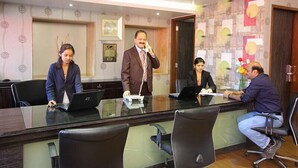 A conference room with a glass table, four chairs, and laptops.