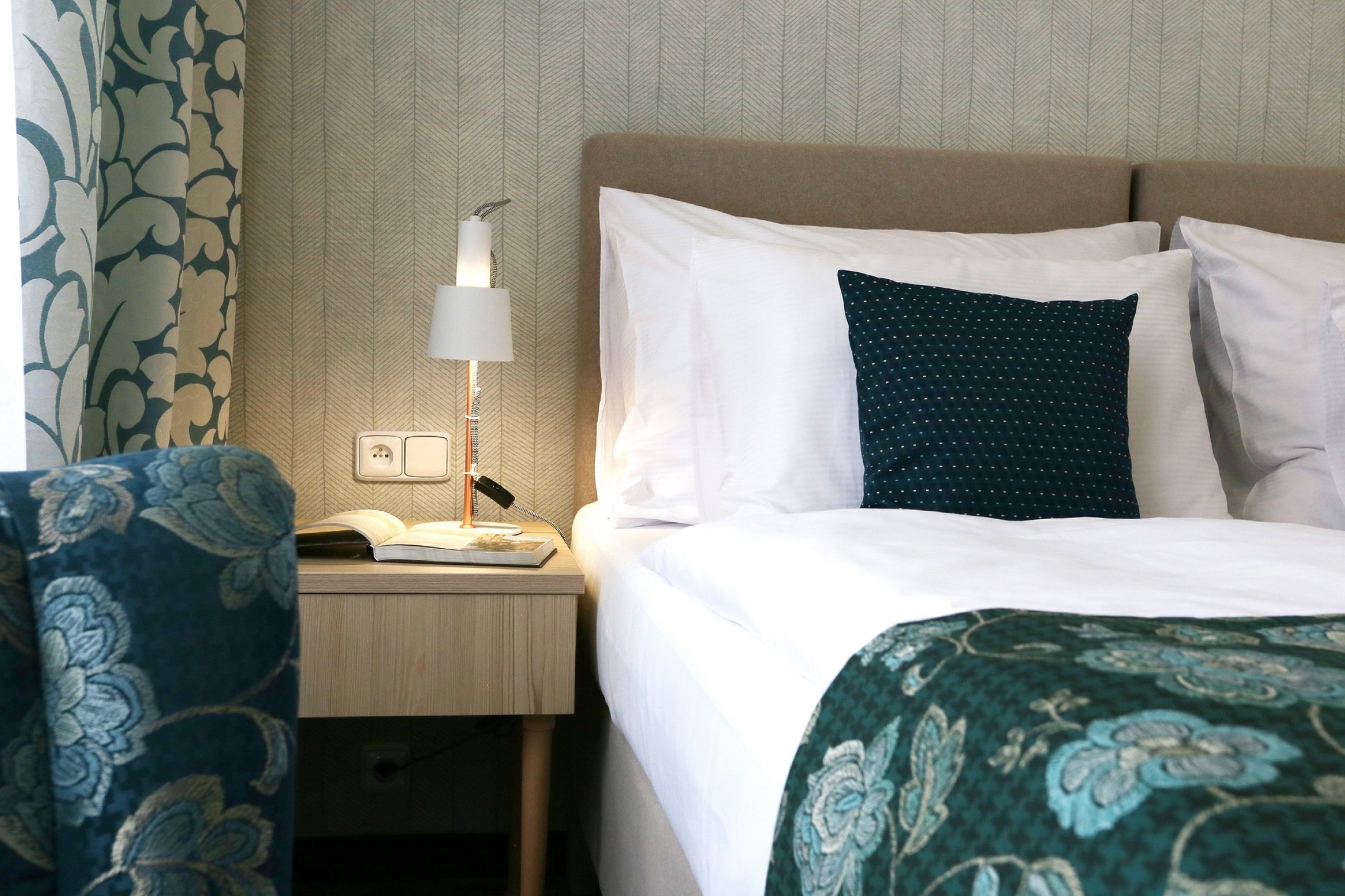 Ein Hotelzimmer mit einem Bett, einem Nachttisch mit Lampe und einem Sessel.