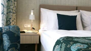 Ein Hotelzimmer mit einem Bett, einem Nachttisch mit Lampe und einem Sessel.