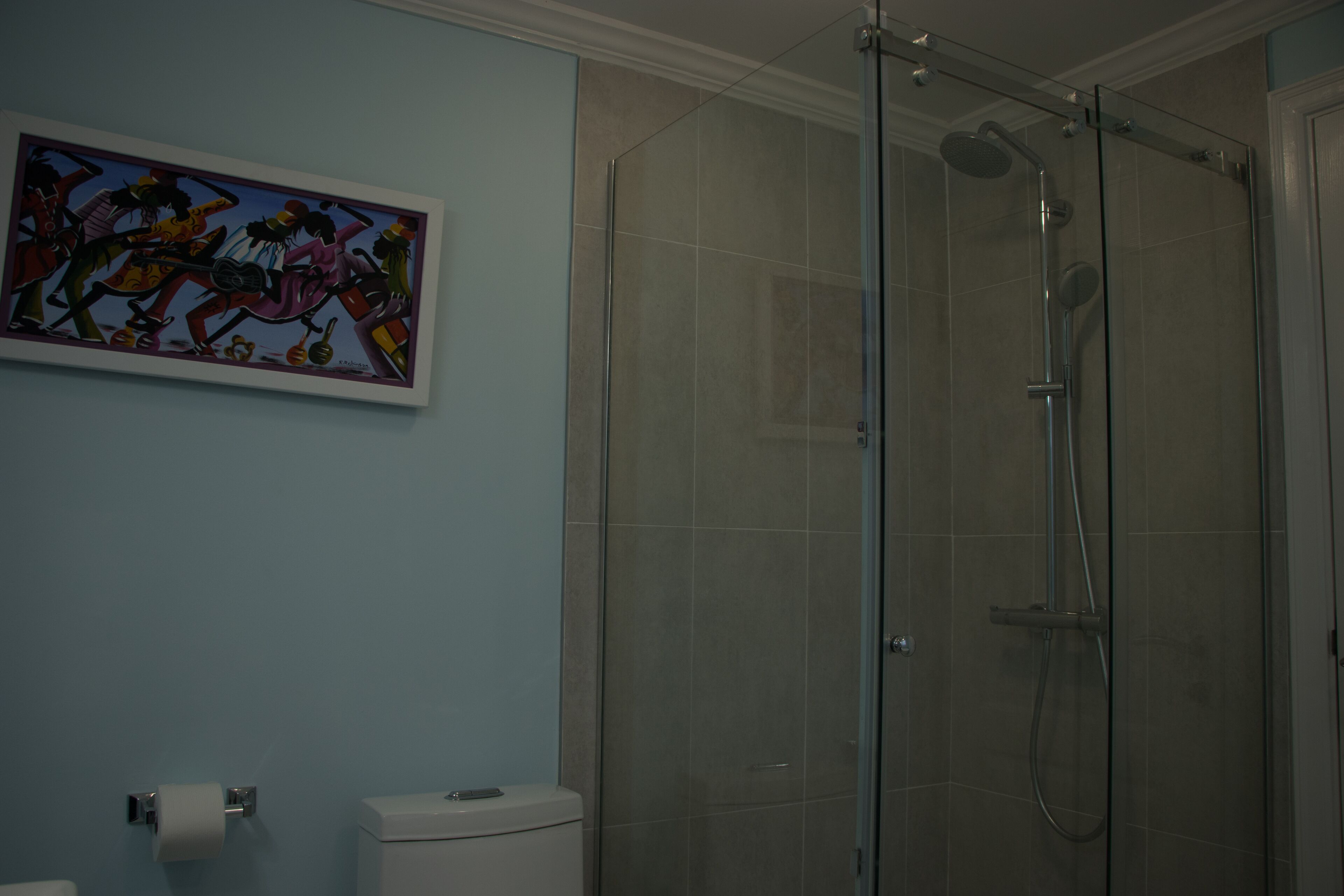 Een badkamer met een douchecabine van glas, een toilet en een rol toiletpapier aan de muur.