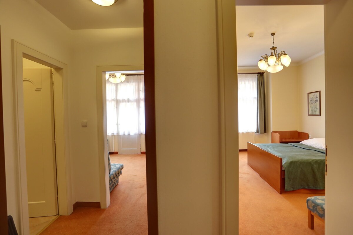 A bedroom with a bed, a chair, and a window with curtains.