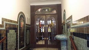 A hallway with a double door, tiled walls, and a marble column. - Art Deco WOLKER by ASTORIA Hotel & Medical Spa (Karlovy Vary)