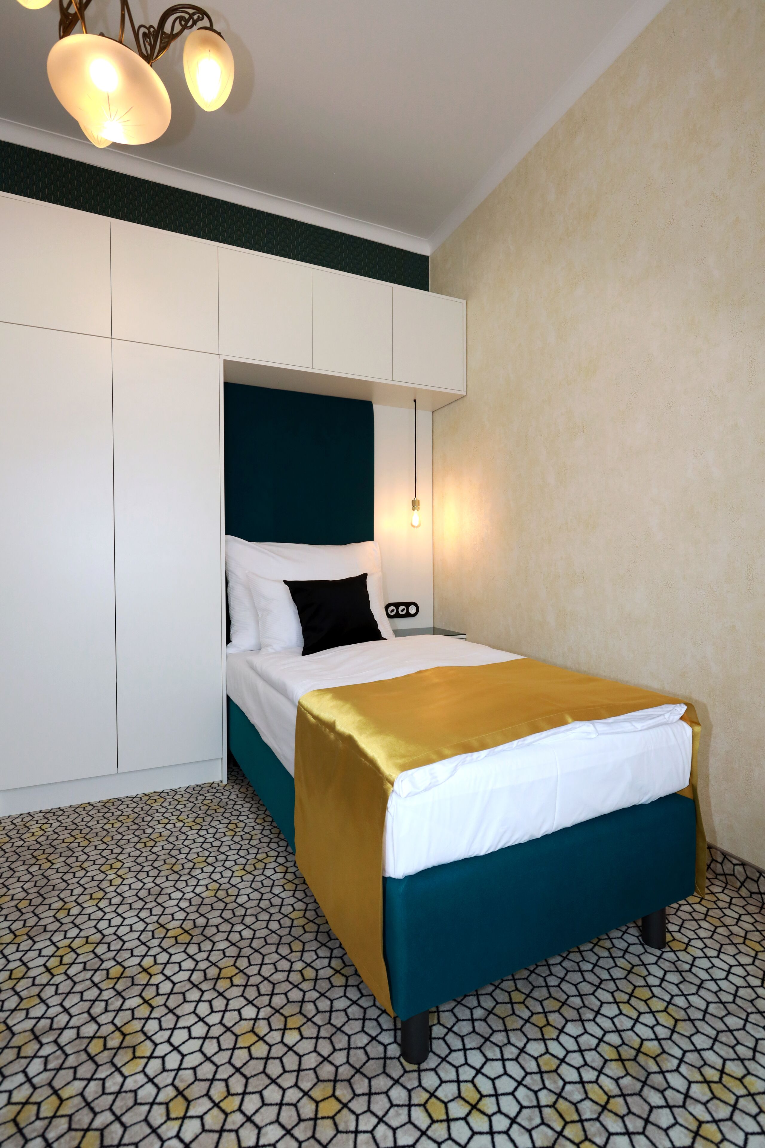 Quarto de hotel com uma cama, um guarda-roupa e um chão estampado.