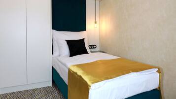 Quarto de hotel com uma cama, um guarda-roupa e um chão estampado.
