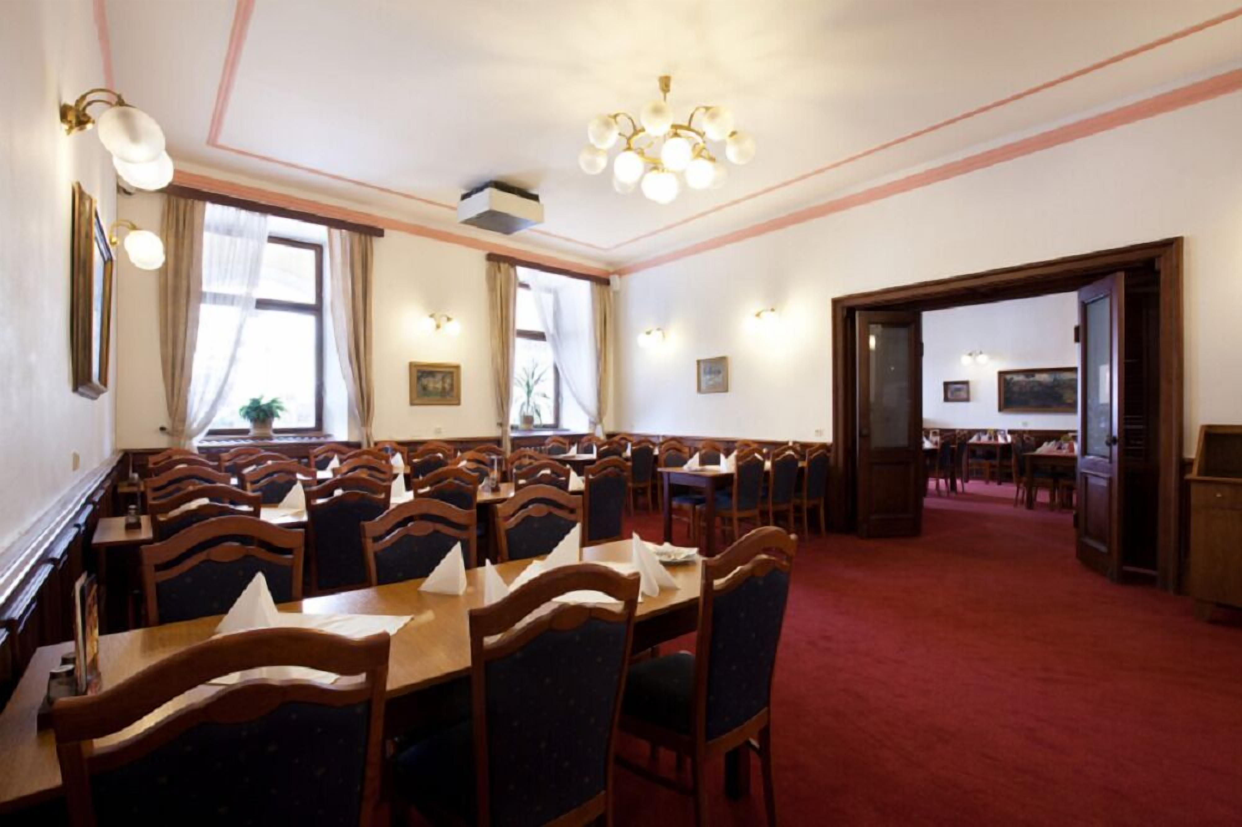 A dining area with multiple tables and chairs, a chandelier, and framed pictures on the walls.