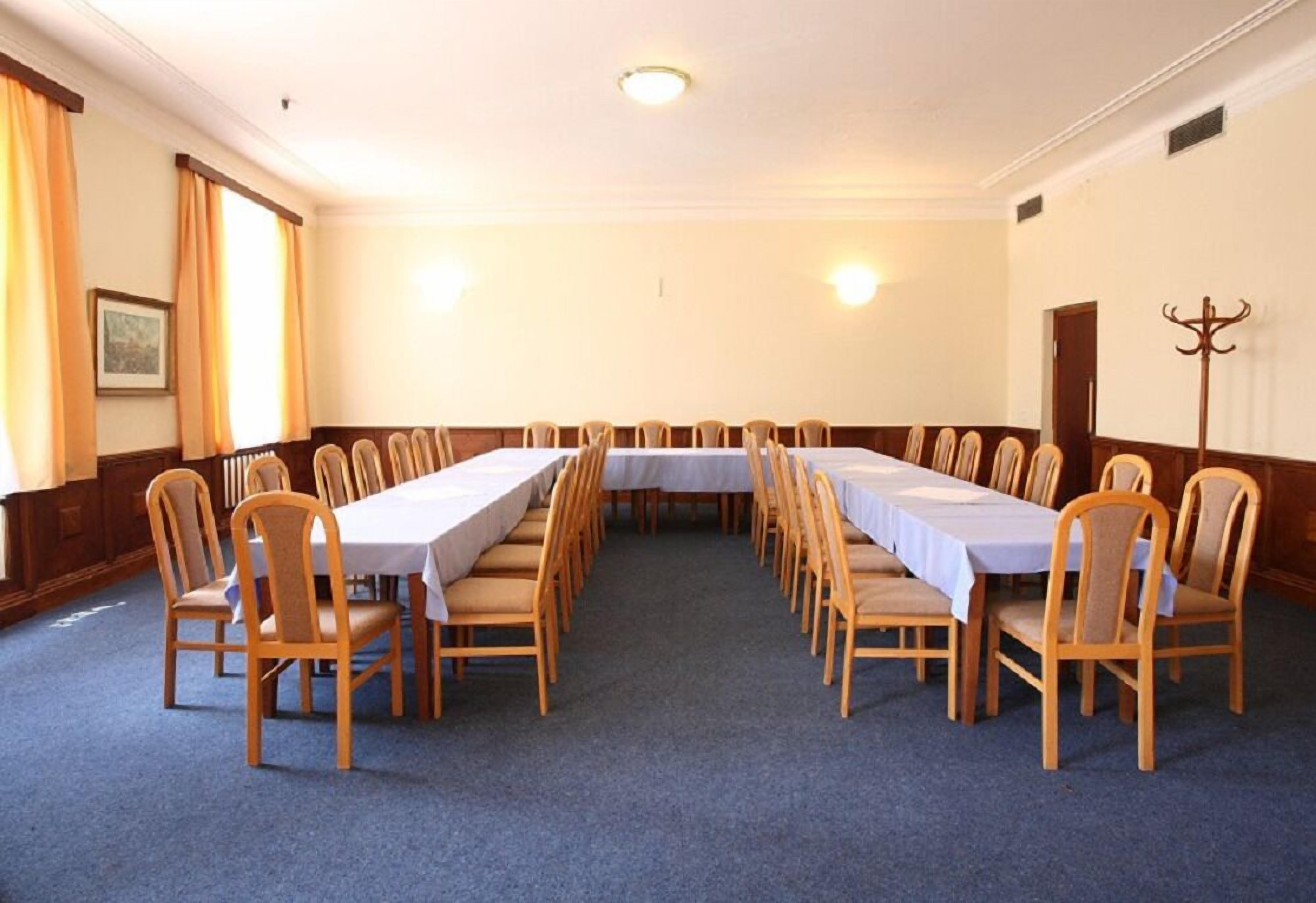 A conference room with a long table and chairs, carpeted floor, and wooden paneling on the walls.