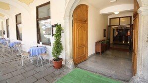 An outdoor seating area with tables and chairs, a wooden door, and a potted plant. - Hotel U Černého orla (Telc)