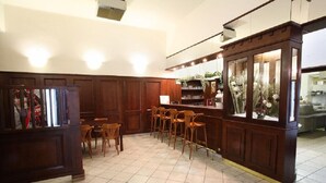 A bar area with wooden paneling, a counter, and several bar stools. - Hotel U Černého orla (Telc)