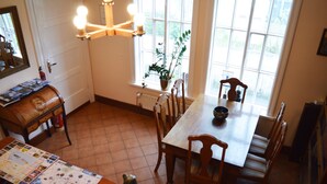 Un coin repas avec une table en bois, des chaises, une plante en pot et une carte posée sur la table.