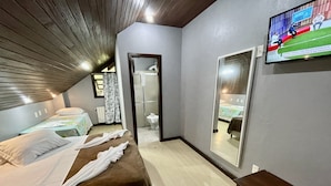 Une chambre d’hôtel avec deux lits, un grand miroir, une télévision et un plafond en bois.