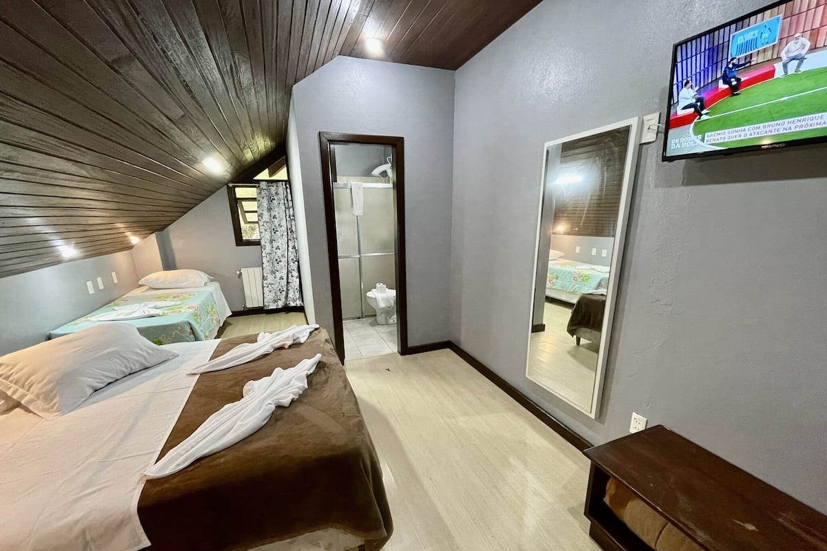 Une chambre d’hôtel avec deux lits, un grand miroir, une télévision et un plafond en bois.