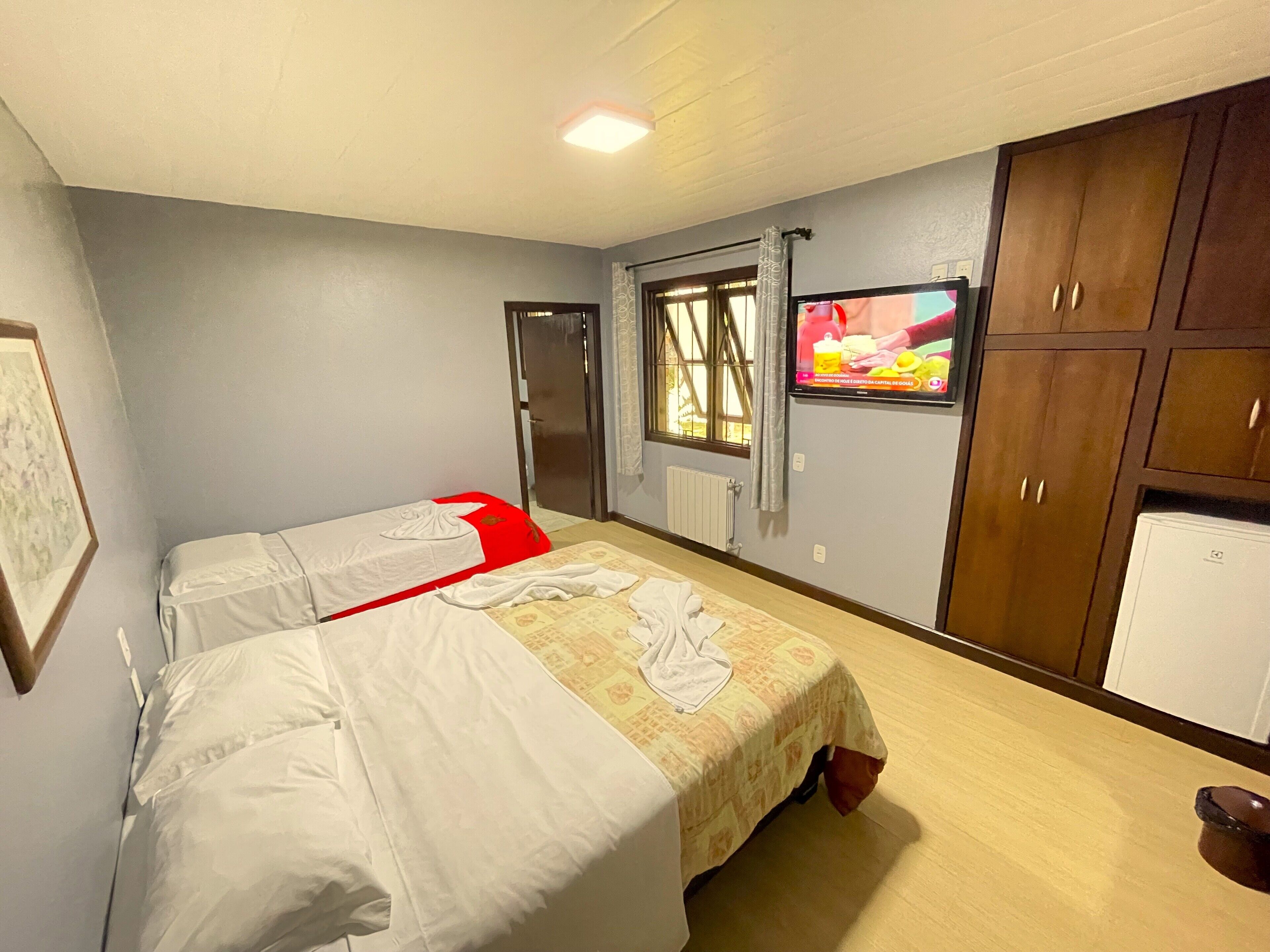 Habitación de hotel con dos camas, televisión, armario y ventana.