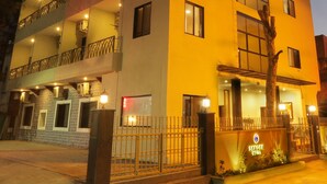 Un hotel de varios pisos con balcones, una entrada bien iluminada y un cartel que indica que es el Sardar Hotel.