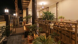 Un espacio interior bien iluminado con una escalera de madera, plantas en macetas y una zona de estar con un banco acolchado.