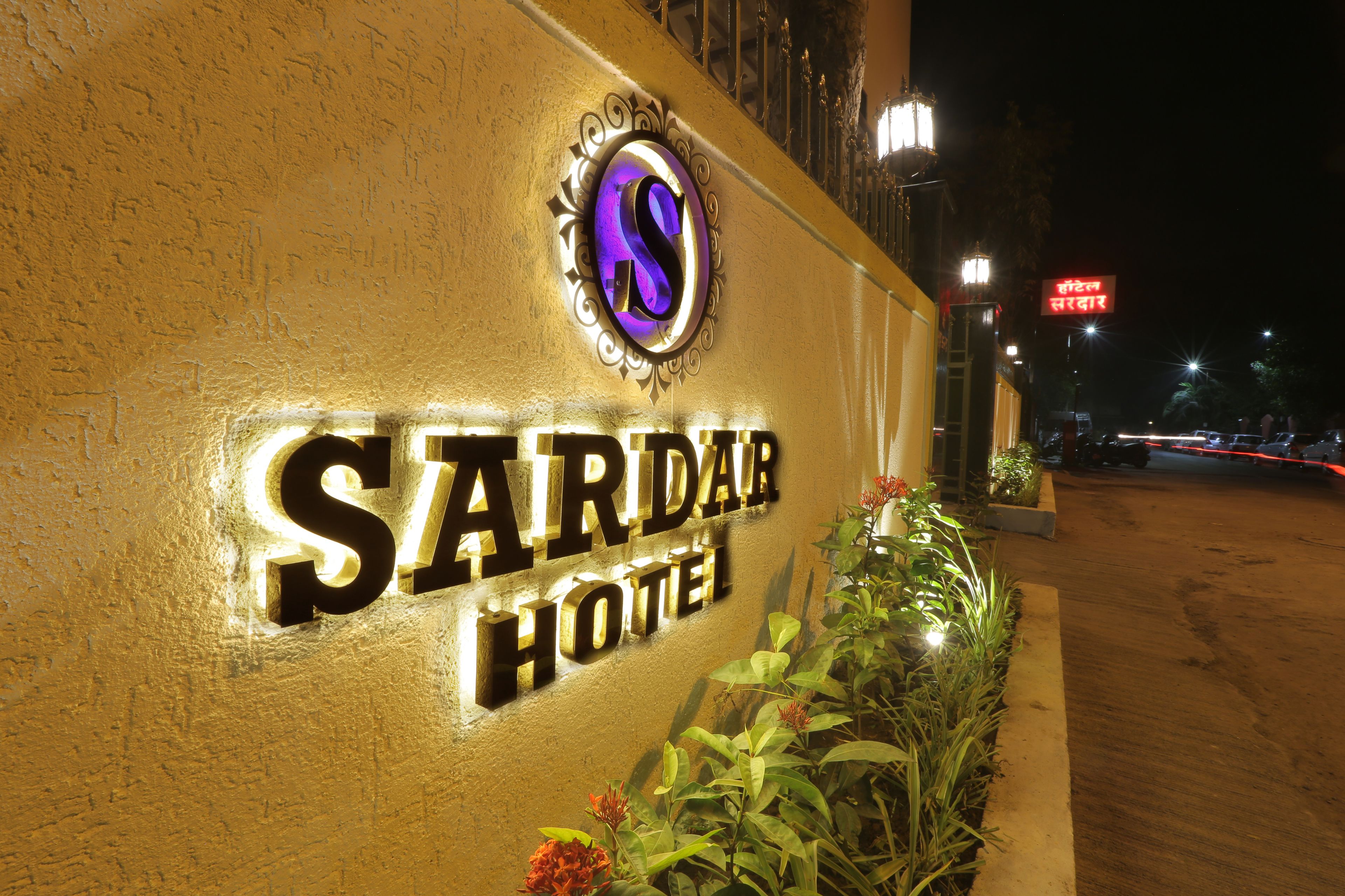 Das Sardar Hotel mit beleuchteter Beschilderung und einer gepflegten Eingangsbereich.