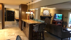 A spacious kitchen with a large island, wooden cabinets, and a dining area with a sofa and chairs.