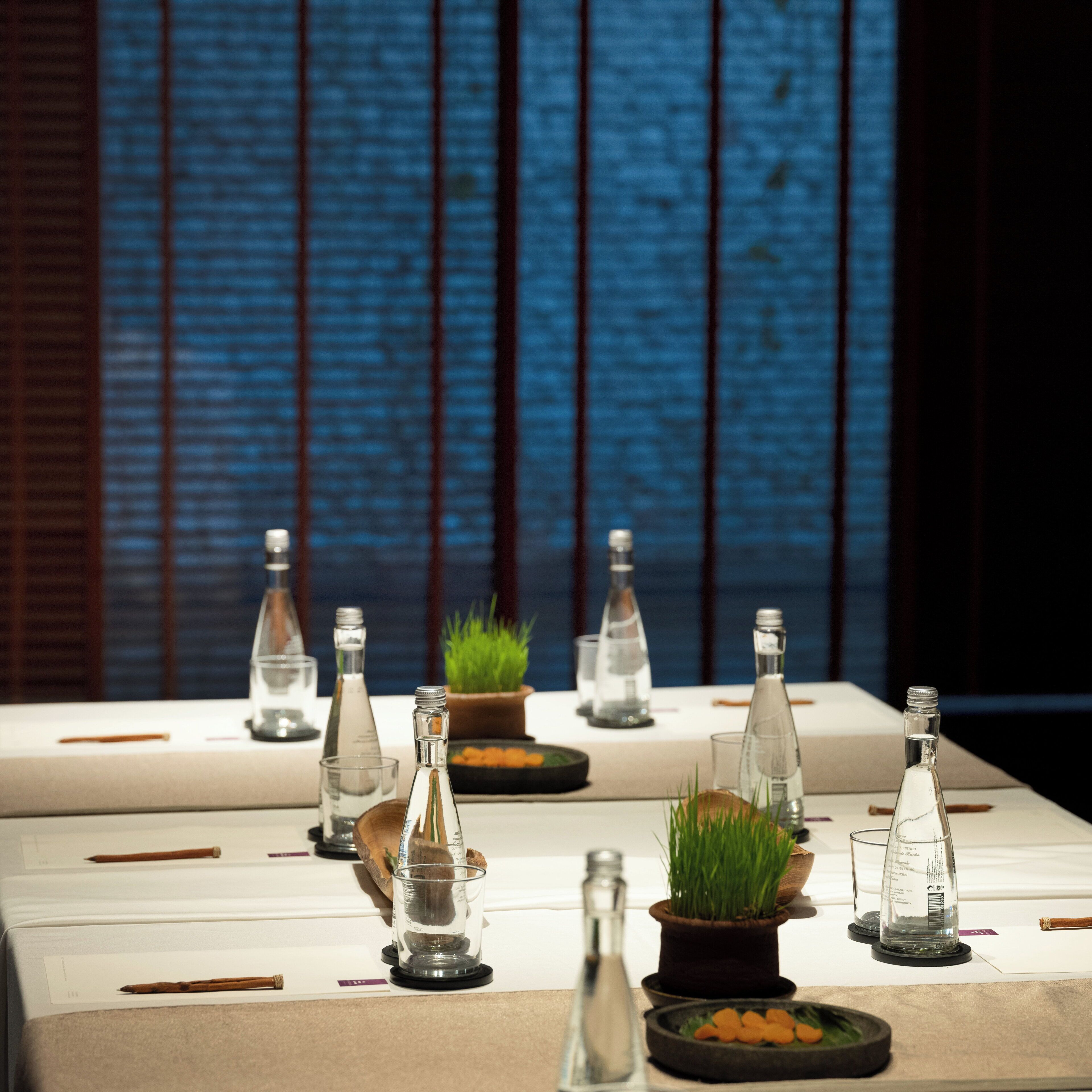 Een tafel gedekt met heldere glazen flessen, een kleine plant in een pot en een paar houten bestek.