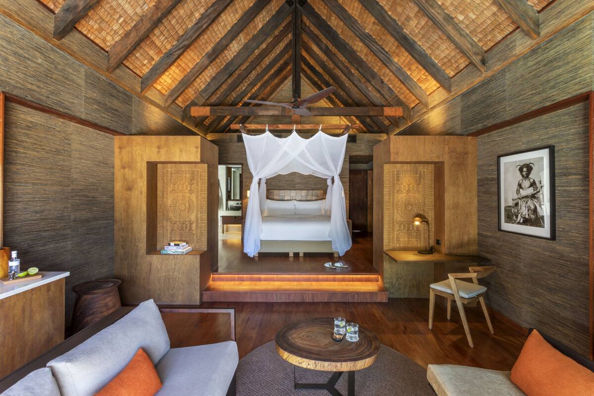 Una habitación con cama, sofá, una mesita y ventilador de techo.