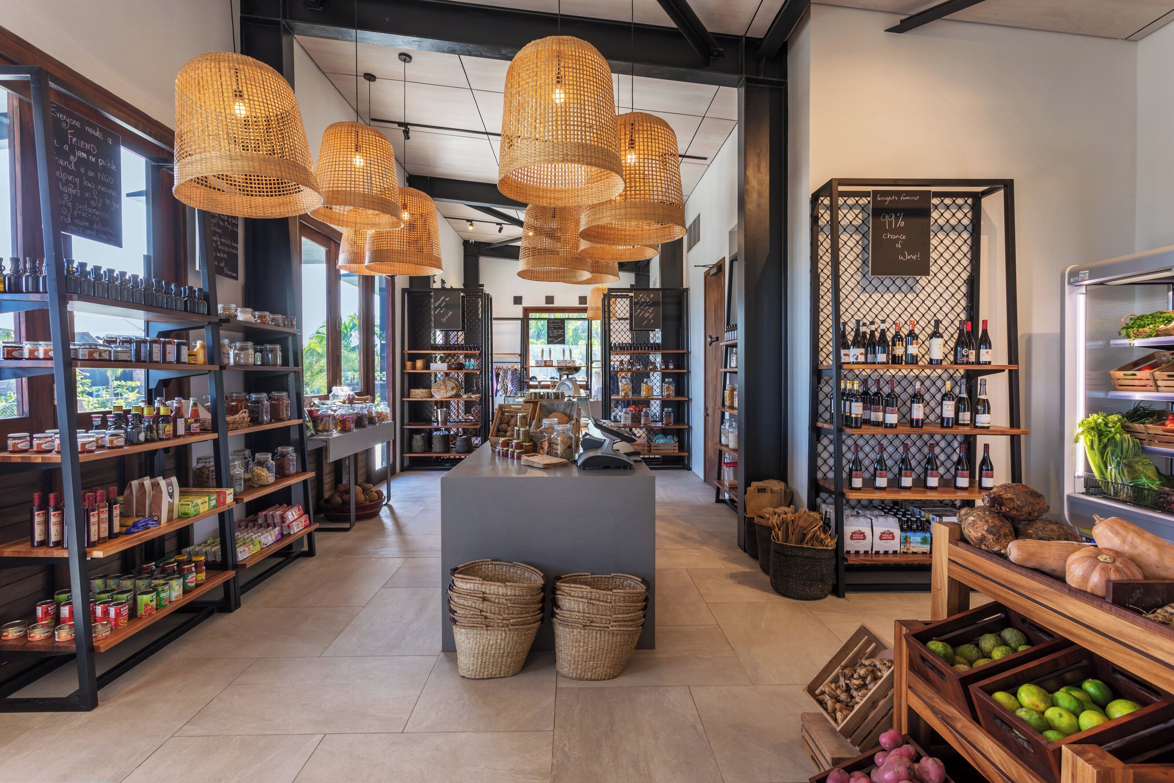 Una tienda bien organizada con estanterías repletas de productos, cestas de mimbre y una exhibición de botellas de vino.