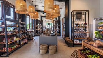 Una tienda bien organizada con estanterías repletas de productos, cestas de mimbre y una exhibición de botellas de vino.