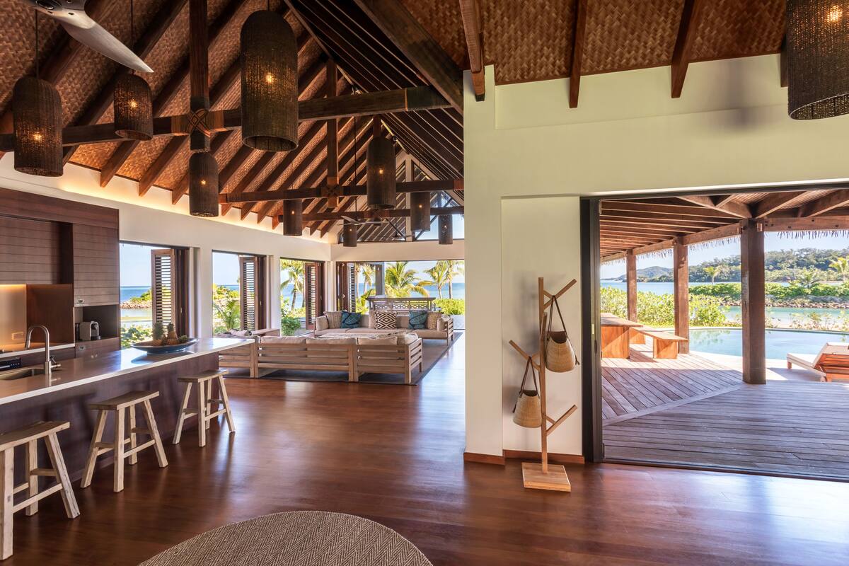 Una cocina amplia con una isla grande, taburetes de madera y vista al océano.