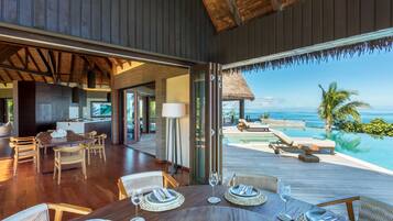 A modern dining area with wooden furniture and a view of the ocean.