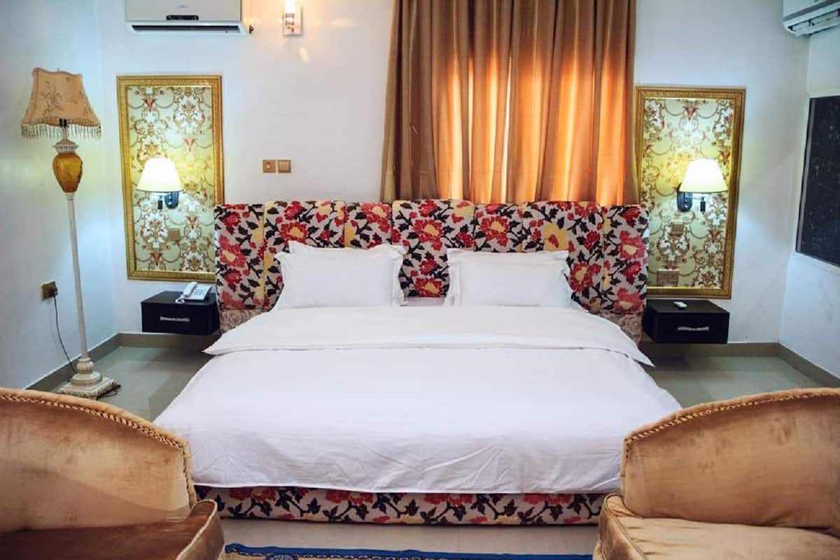 A hotel room with a bed, two nightstands, a lamp, and a floral-patterned headboard.