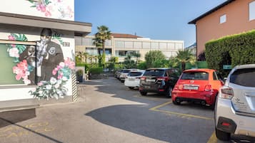 A parking lot with several cars, a building with a mural, and a hotel sign.