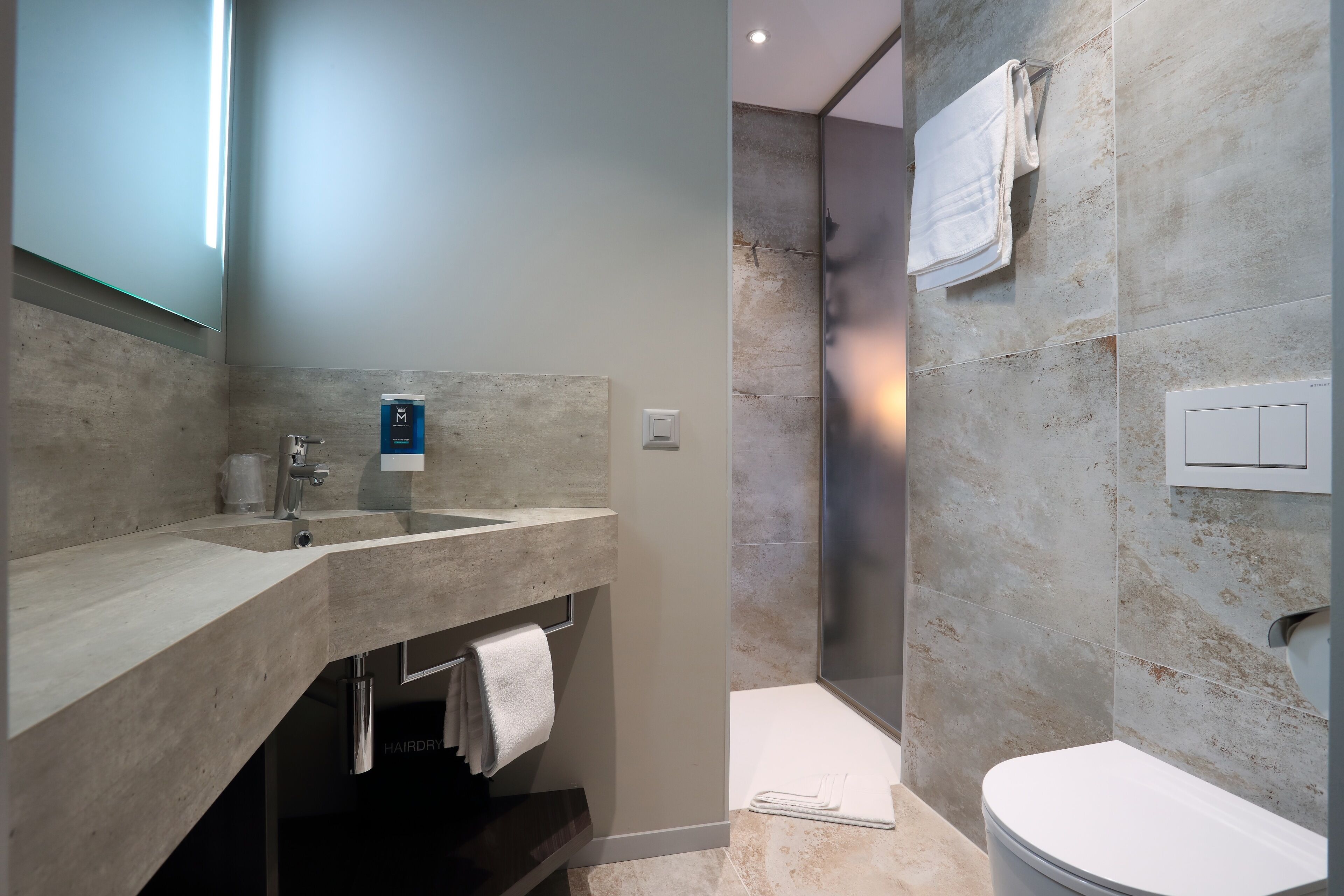 A modern bathroom with a large sink, mirror, and shower area.