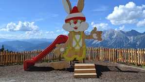 Una estructura de juego de madera con un tobogán y la figura de un conejo.