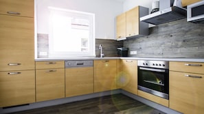 A modern kitchen with wooden cabinets, a built-in oven, and a window providing natural light.