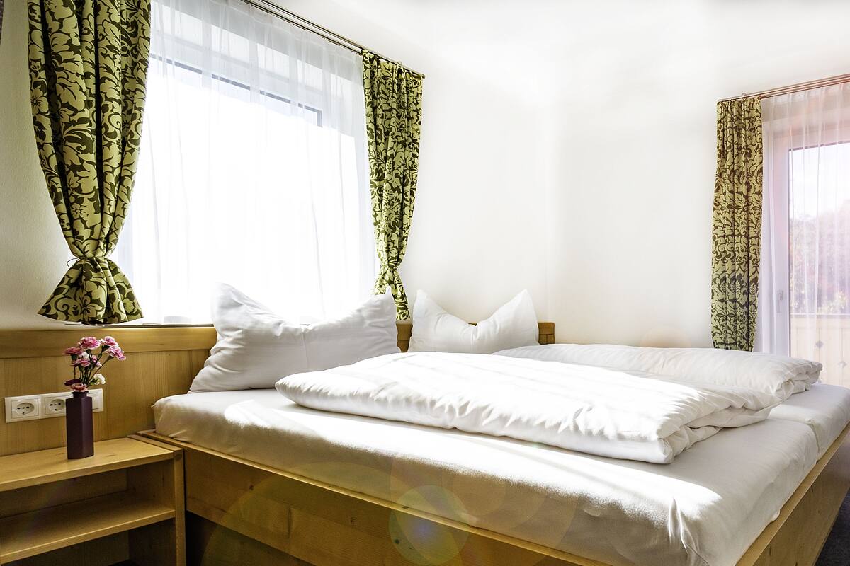 Une chambre d’hôtel avec un lit, une table de chevet et une fenêtre avec des rideaux.