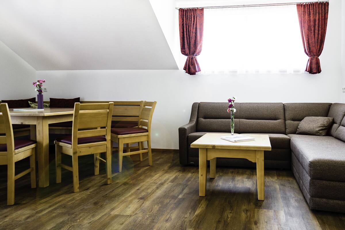 Un coin repas avec une table et des chaises, un canapé et une fenêtre avec des rideaux.
